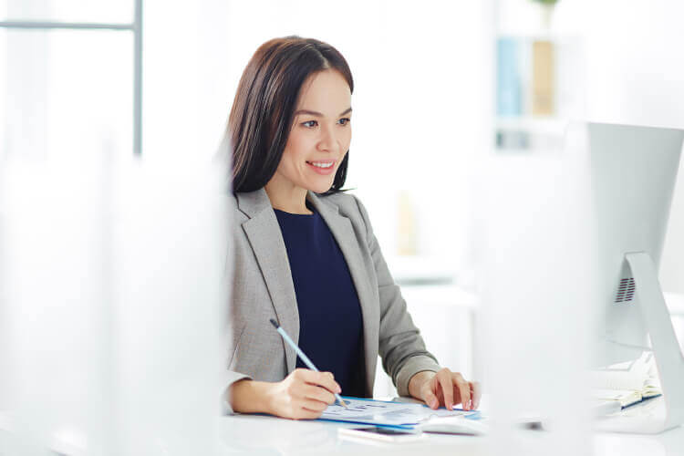 Mujer sonriendo viendo un computador y escribiendo